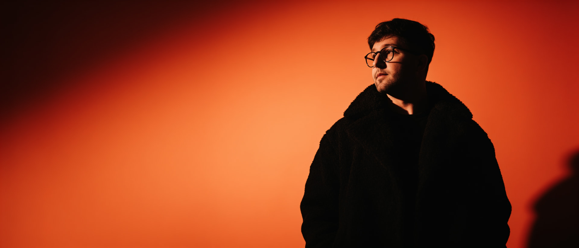 Portrait of Alan Krevo lit against a burning orange backdrop