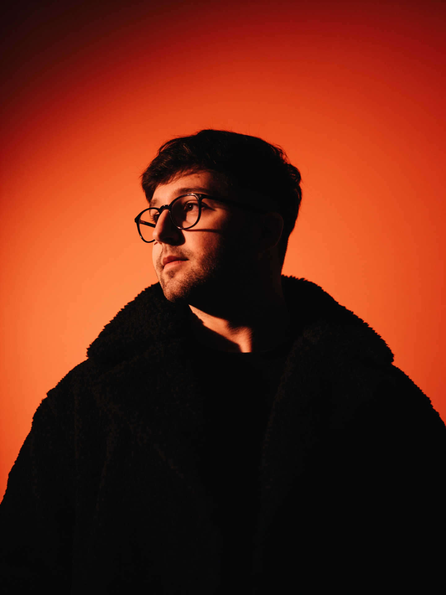 Portrait of Alan Krevo lit against a burning orange backdrop